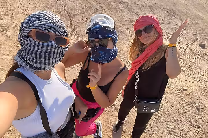 Friends posing in Hurghada desert with scarves and goggles on 6-hour Jeep safari adventure, BBQ dinner and show