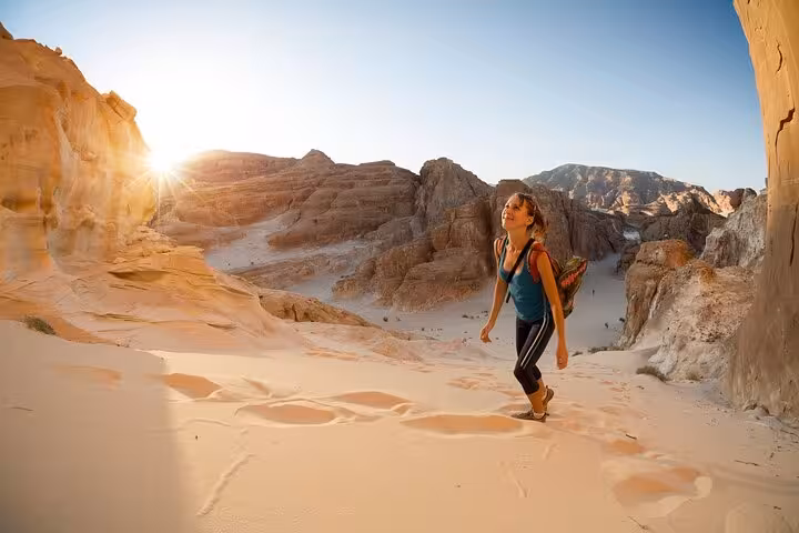 Traveler hiking golden sand dunes at sunset on Hurghada jeep desert safari before Bedouin dinner and stargazing