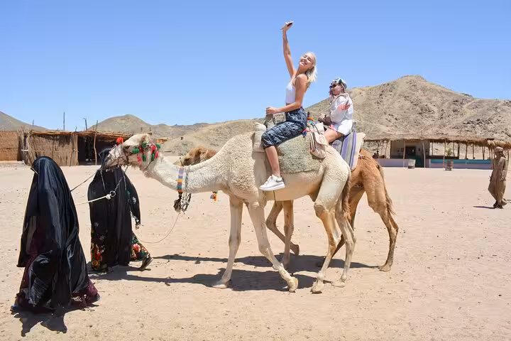Tourists riding camels at a Bedouin village near Hurghada during Jeep Super Safari with dinner and show