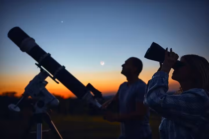 Travelers stargaze at sunset with telescope on Hurghada Jeep safari tour, ending with traditional Bedouin dinner