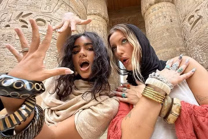 Friends posing at carved Luxor temple columns on Hurghada to Luxor excursion with King Tut tomb entry