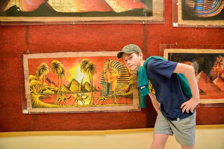 Traveler browsing Egyptian papyrus art in Luxor bazaar on Hurghada to Valley of the Kings day tour