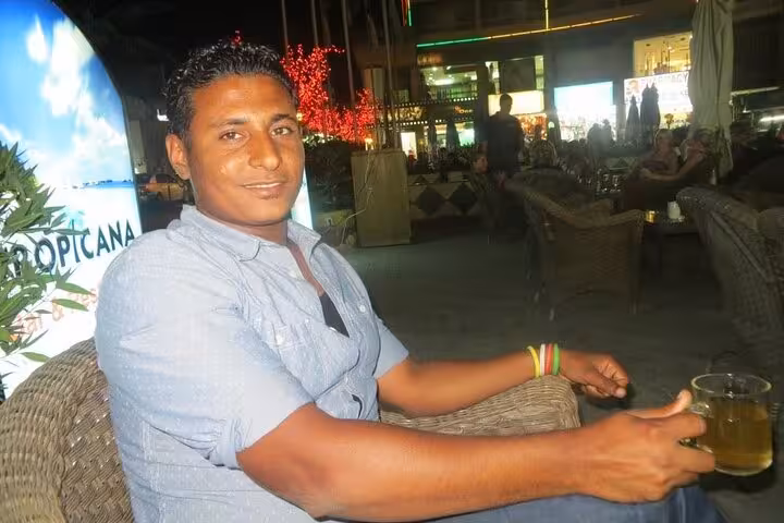 Tourist relaxing at a Hurghada marina café at night, enjoying a drink during an evening city tour