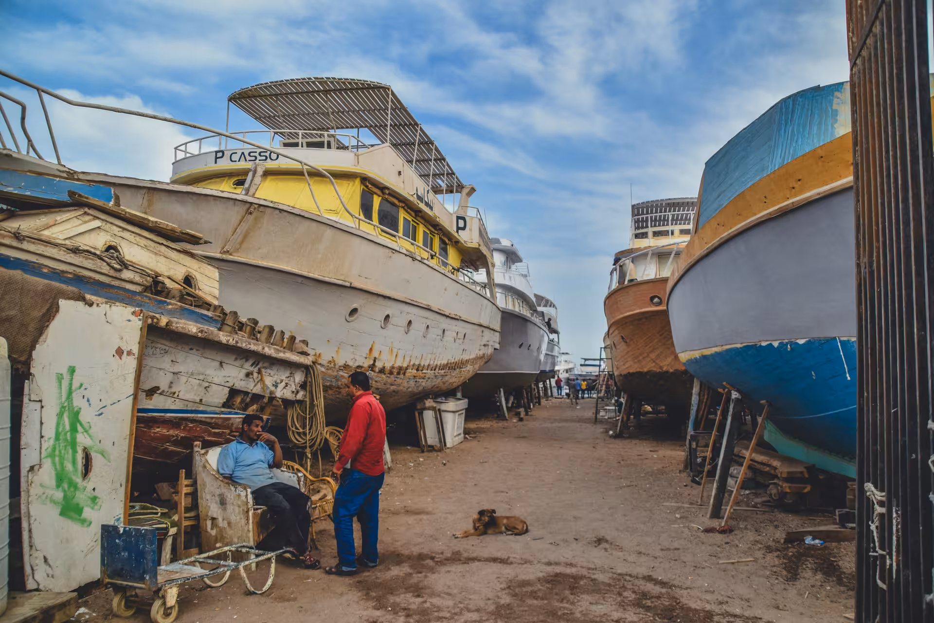 Boats dry-docked at Hurghada's old port shipyard with workers resting nearby