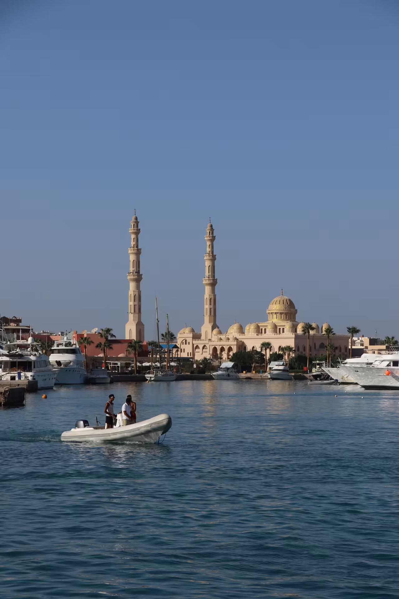 Small inflatable boat on Hurghada marina with mosque minarets and golden dome in background
