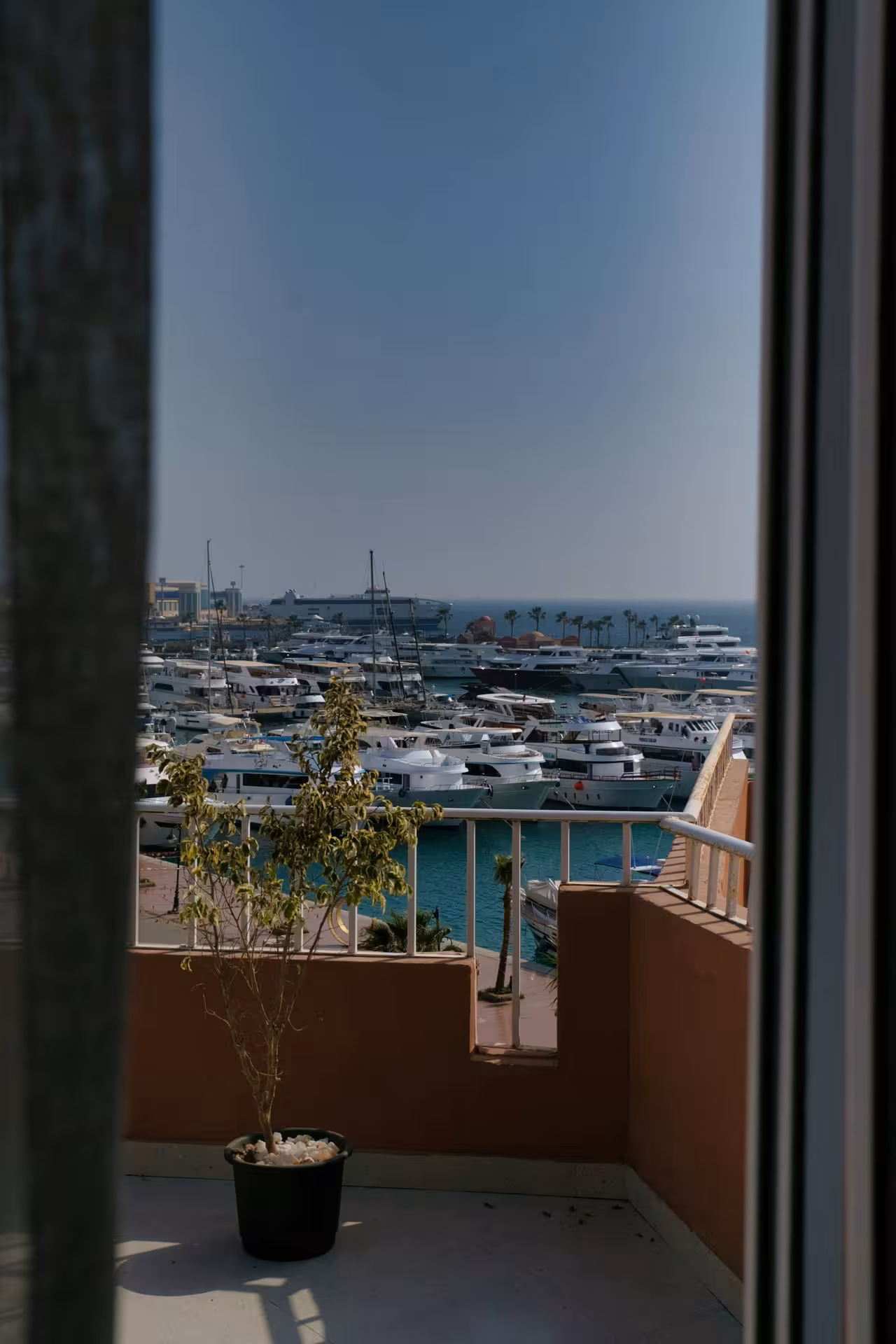 View from balcony overlooking Hurghada Old Port marina with yachts and boats docked in turquoise water