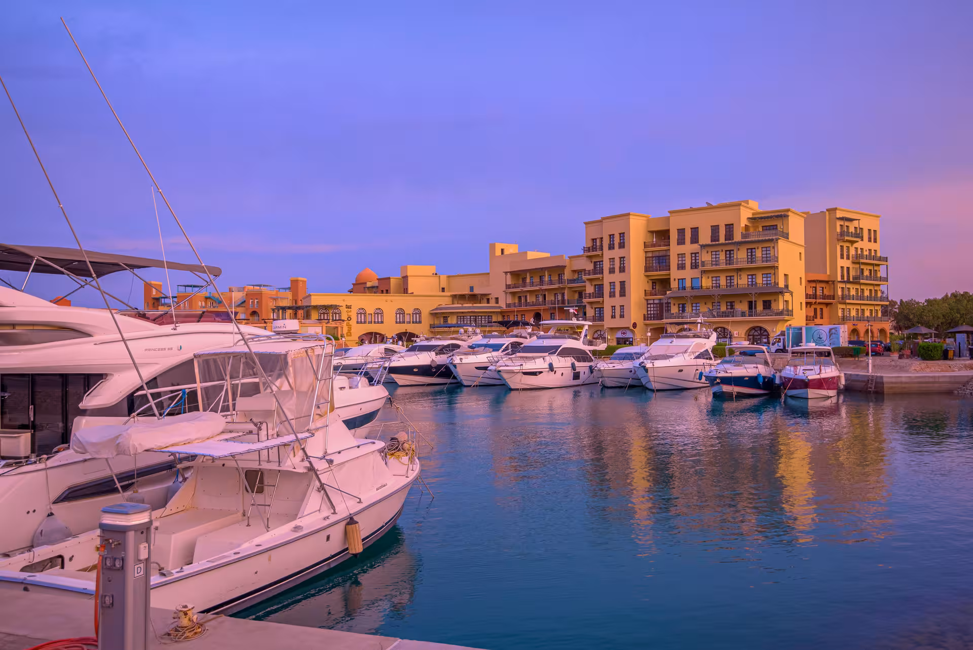 Hurghada Old Port marina at sunset with white yachts docked and colorful waterfront buildings