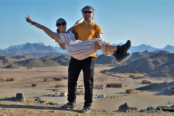 Couple posing on Hurghada desert viewpoint after quad bike ride, scenic mountains backdrop on ATV safari trip