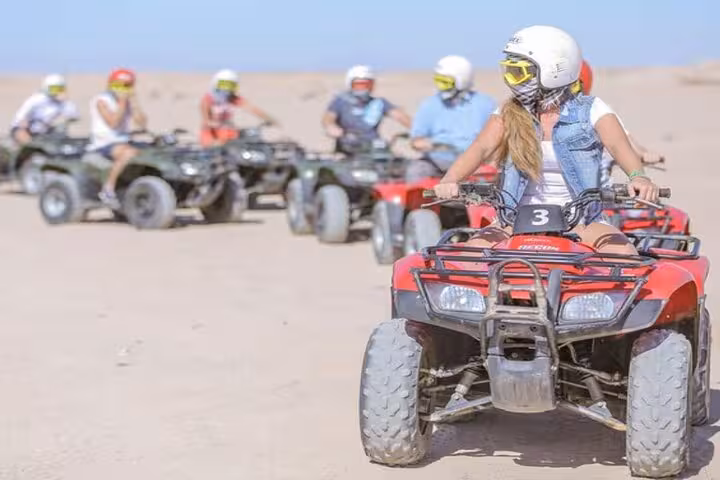 Woman riding quad bike in Hurghada desert convoy, 1-hour family safari adventure with dinner and live show