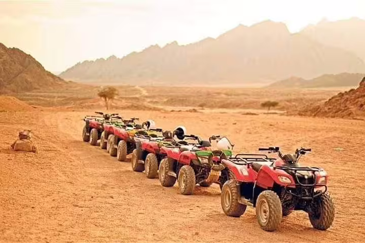 Row of quad bikes lined up on a desert track at golden hour for a sunset desert safari adventure