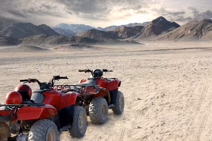 Two red ATVs on Hurghada desert track with mountain views, quad bike safari tour with transfer and BBQ