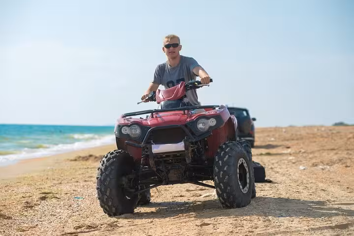 Rider on red ATV quad cruising Hurghada beach, Red Sea coast desert adventure tour by sea and mountains