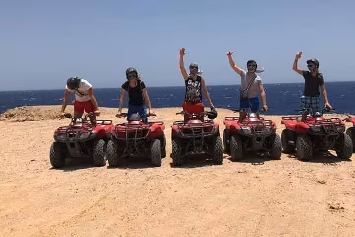 Group on red quad bikes by the Red Sea coast in Hurghada, ready for ATV sea and mountain desert adventure