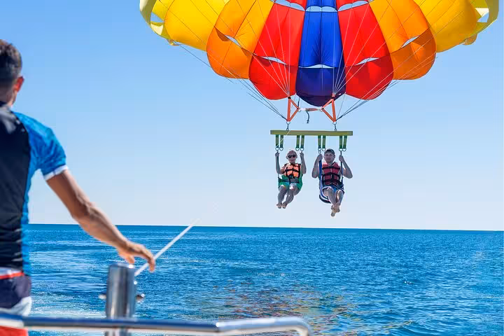 Hurghada Red Sea parasailing takeoff from boat, two riders in harness under bright parachute