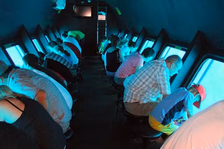 Tourists leaning to watch coral reefs through panoramic windows on Hurghada 2-hour semi-submarine adventure