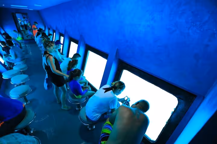 Inside Hurghada semi-submersible boat, guests watch Red Sea coral reefs through underwater windows