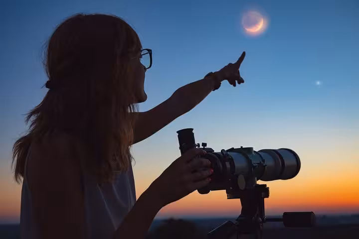 Guest with telescope at sunset on Hurghada stargazing jeep safari, spotting crescent moon before dinner