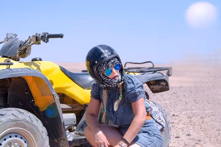 Tourist in helmet beside yellow quad bike on Hurghada desert safari, ATV ride with hotel transfer and BBQ