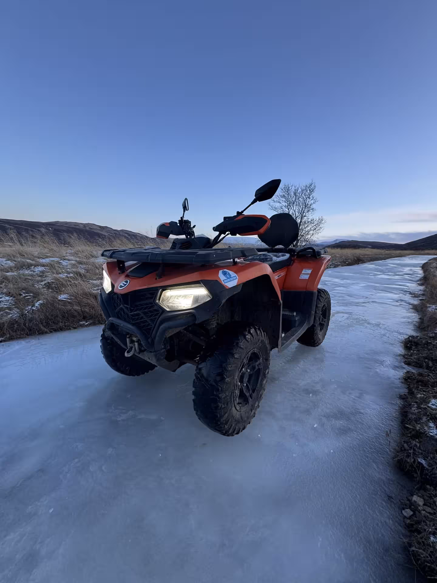 Red ATV quad bike parked on icy trail with mountain views in Husafell Iceland