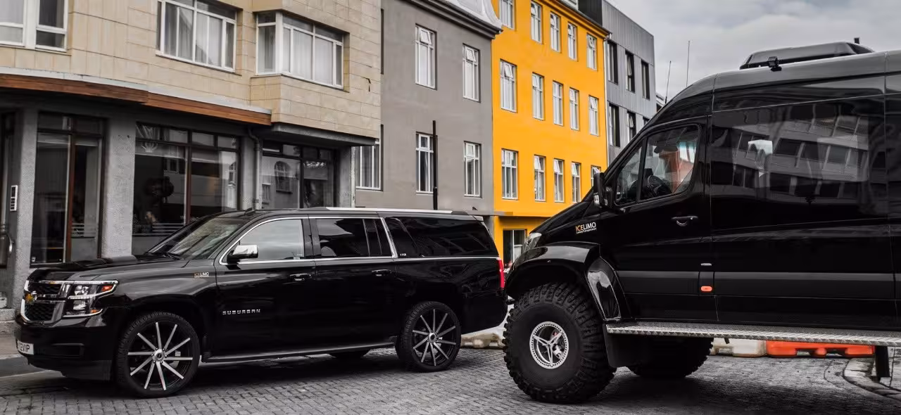 Black Chevrolet Suburban SUV and luxury black van parked on cobblestone street in Iceland