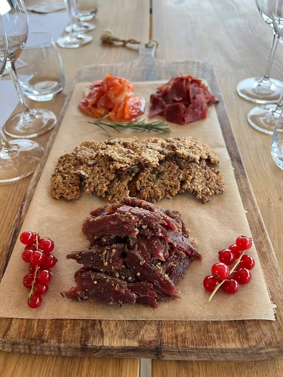 Hidden Fjord Escape local food tasting board with seasoned cured reindeer meat, seeded crackers, smoked salmon, and fresh red currants.