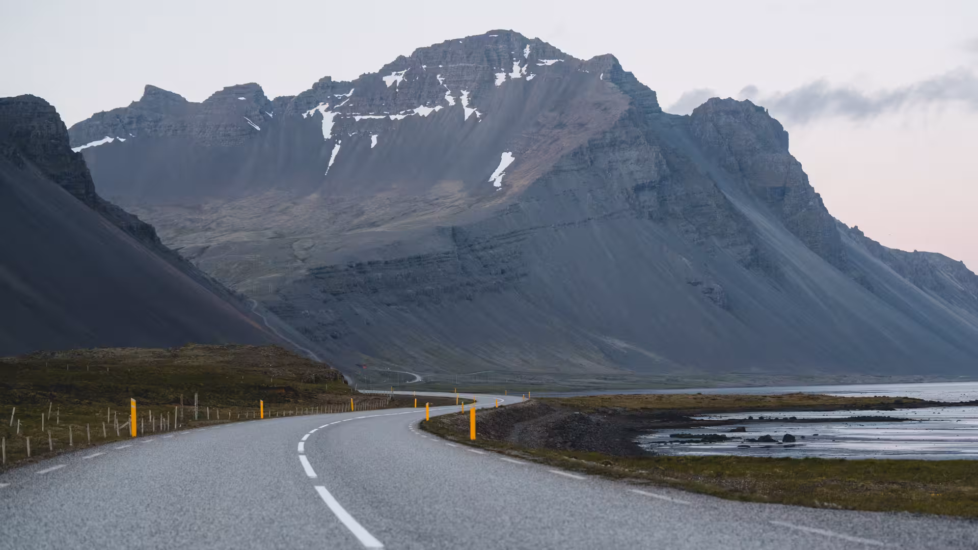 Scenic drive toward Hvalfjörður, winding coastal road with dramatic Iceland mountains on fjord sightseeing tour