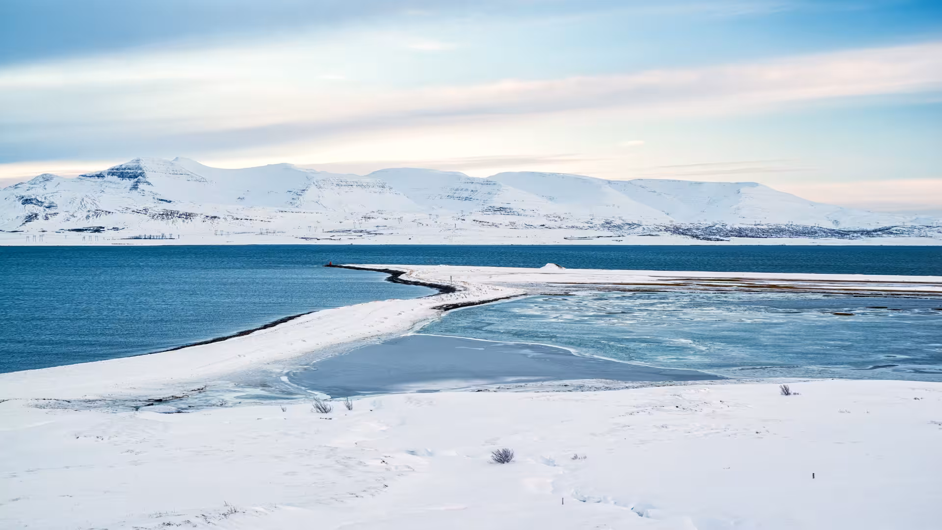 Snowy Hvalfjörður coastline and blue fjord waters, Iceland scenic fjord blast tour with Hvammsvík baths option