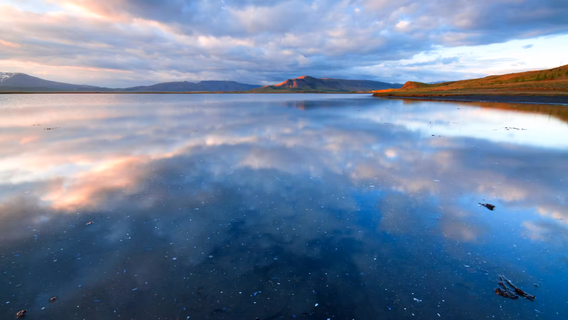 Mirror-calm Hvalfjörður fjord at sunset, Iceland scenic drive tour with optional Hvammsvík geothermal baths
