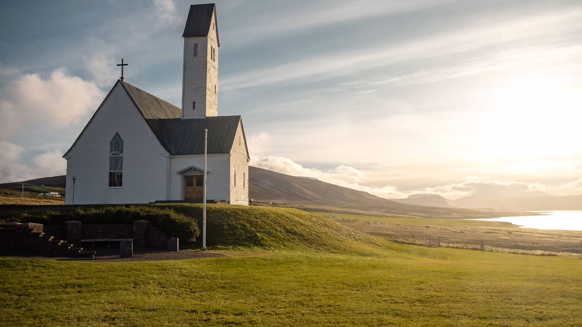 White Icelandic church overlooking Hvalfjörður fjord on scenic drive tour from Reykjavik at golden hour