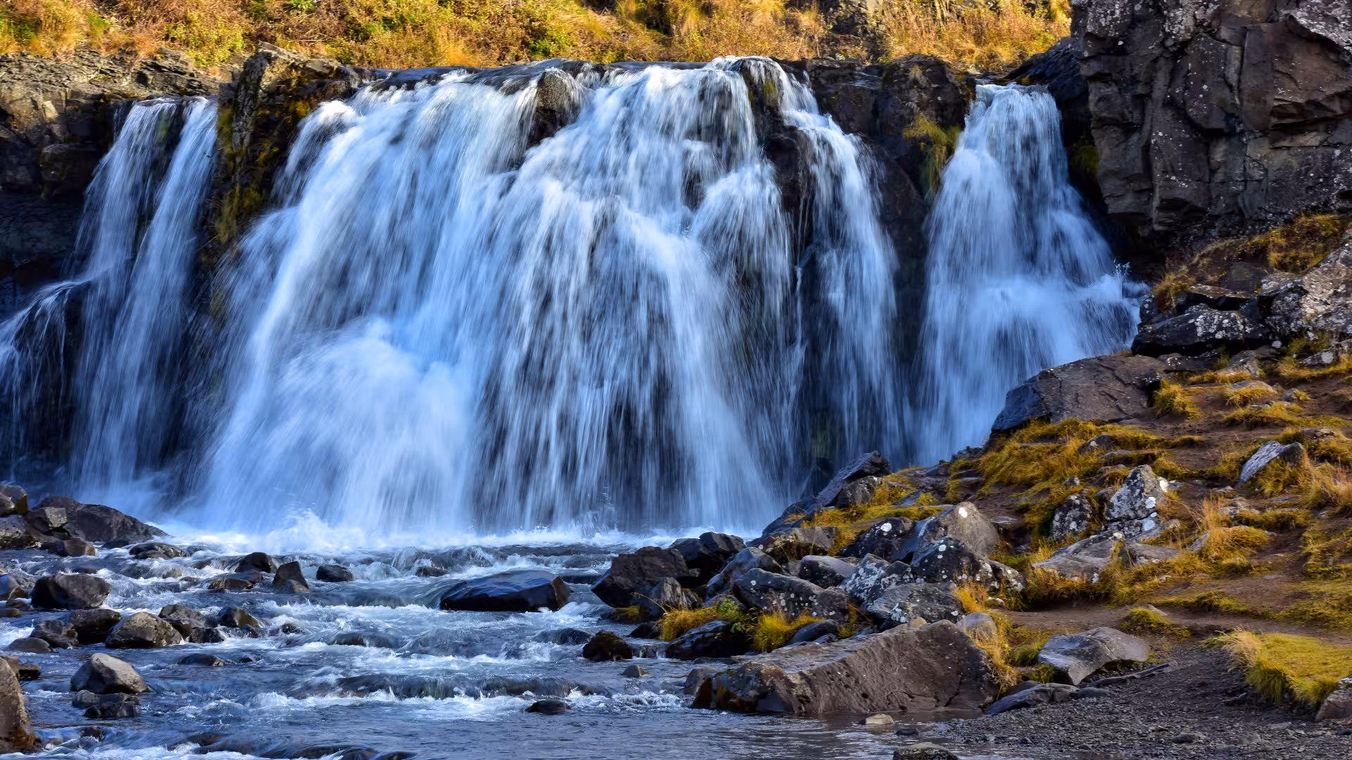 Waterfall stop on the Hvalfjörður Scenic Fjord Blast tour, cascading falls over basalt rocks in West Iceland