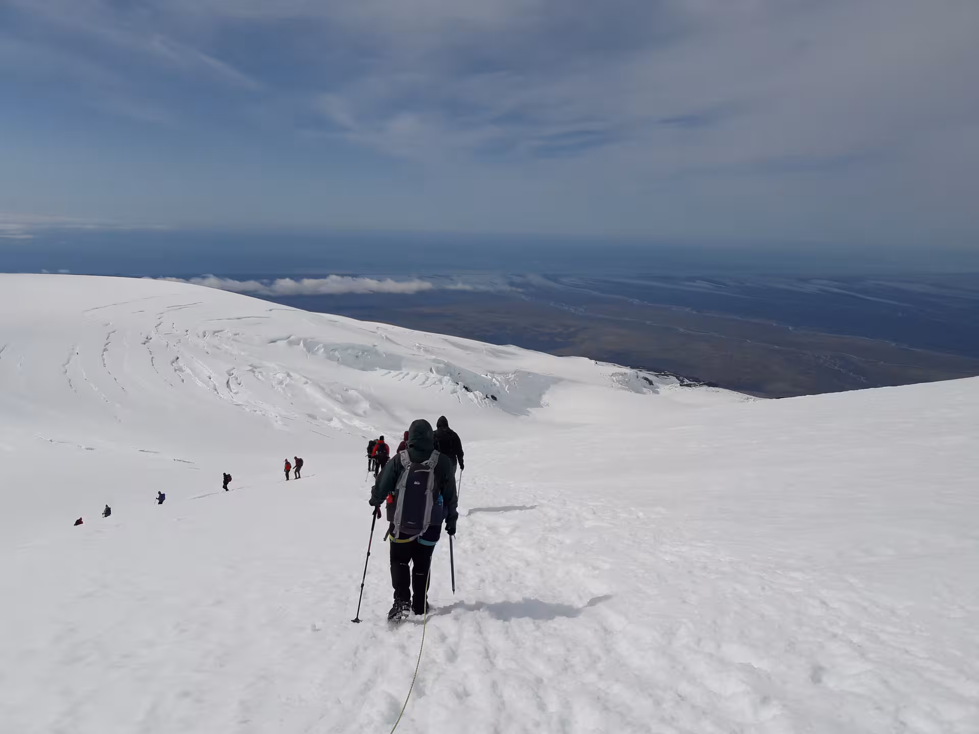 Hikers descending snowy Hvannadalshnjukur glacier with vast Iceland landscape below