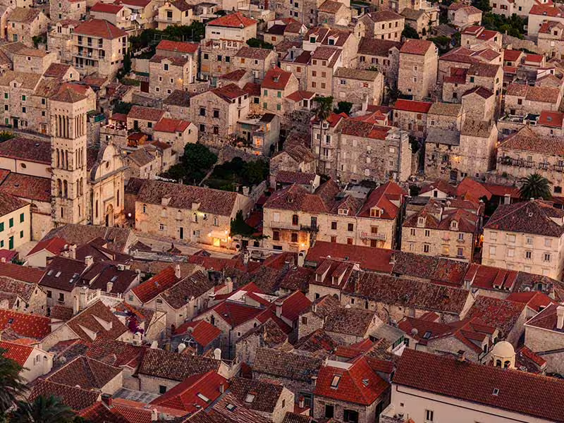 Sunset view over stone rooftops and cathedral bell tower in Hvar Town, scenic private boat tour stop