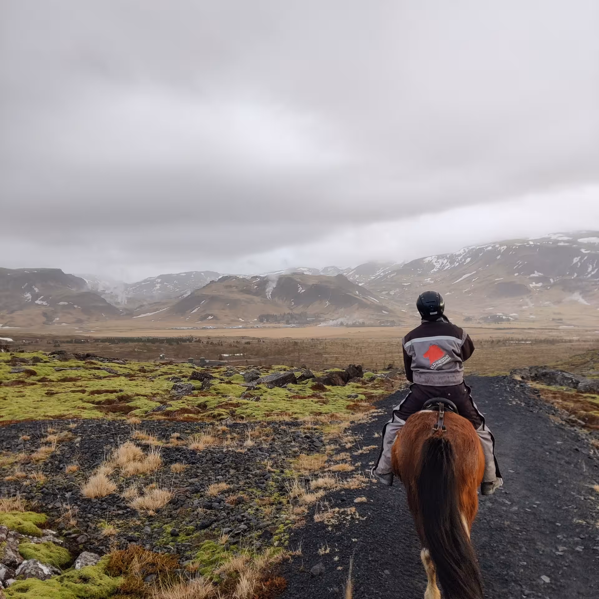 Rider on an Icelandic horse exploring dramatic mountain landscape on a guided horse riding tour in Hveragerdi Iceland
