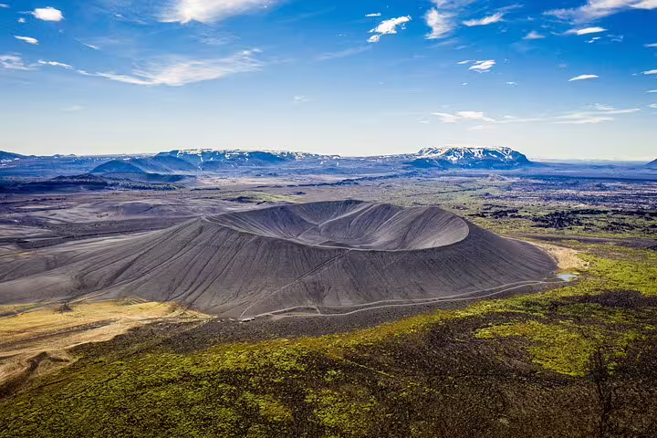 Aerial view of Hverfjall volcanic crater near Lake Myvatn with snow-capped mountains in background, Iceland