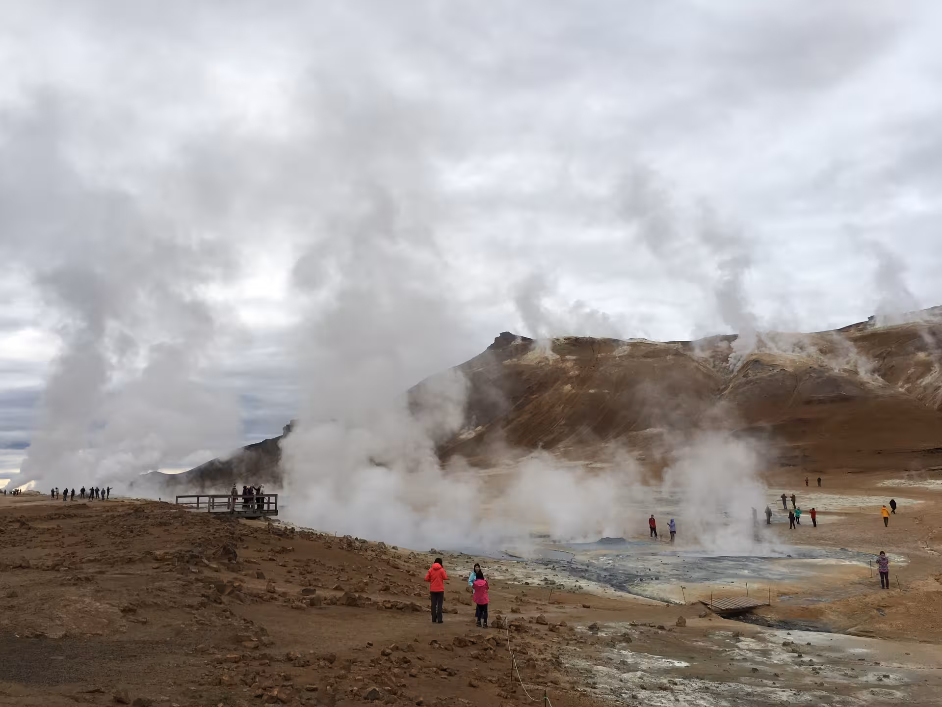 Tourists exploring Hverir geothermal area with massive steam vents and colorful volcanic hills at Lake Myvatn day tour