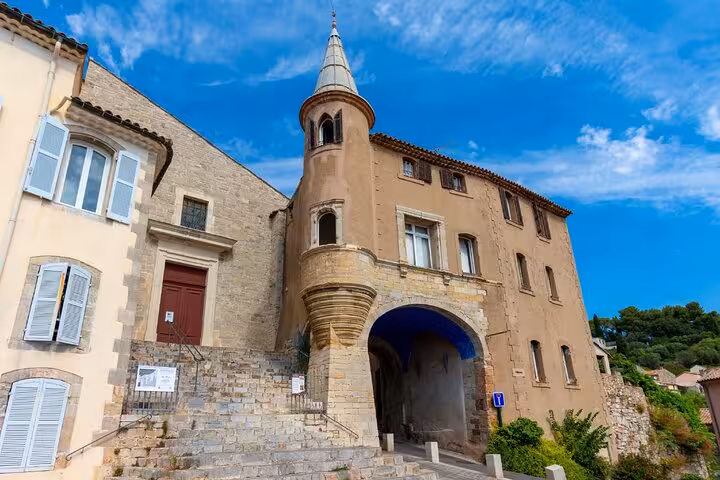 Historic stone building with turret and arched gateway in Hyères, France under blue sky