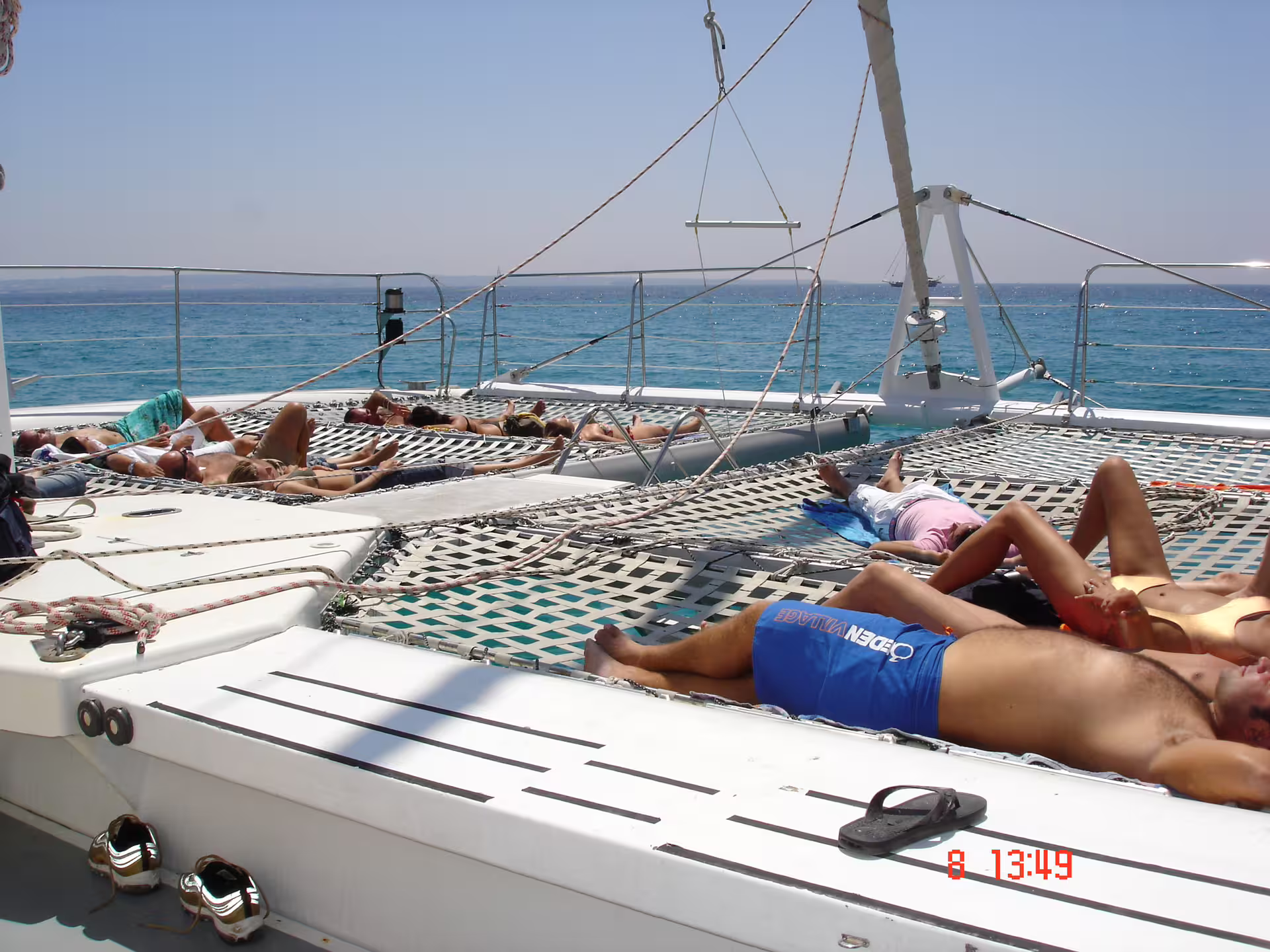 Guests sunbathing on catamaran net deck on Ibiza to Illetas Formentera cruise with food and drinks