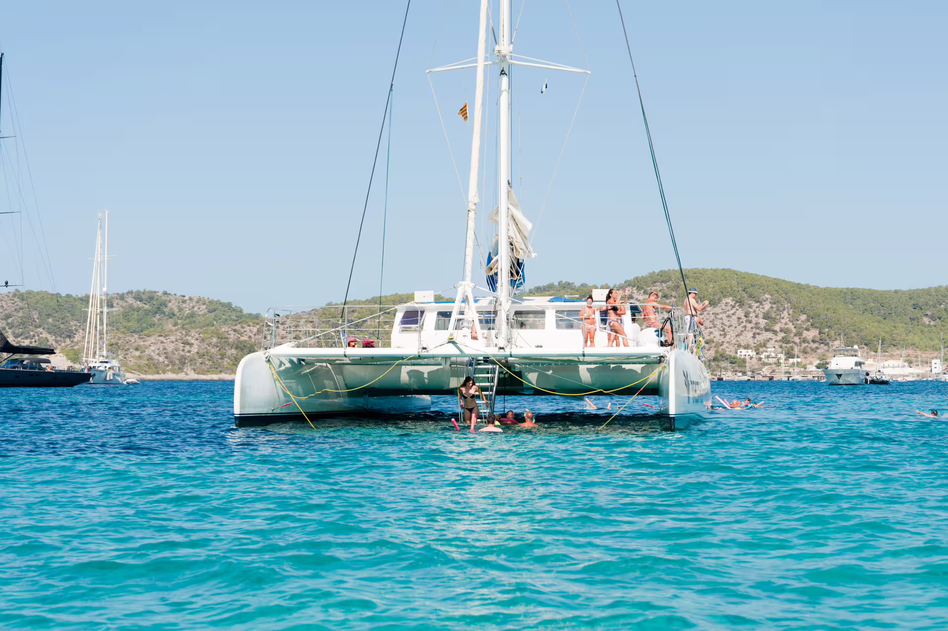 Catamaran anchored at Illetas, Formentera with guests swimming and snorkeling on Ibiza day trip with food