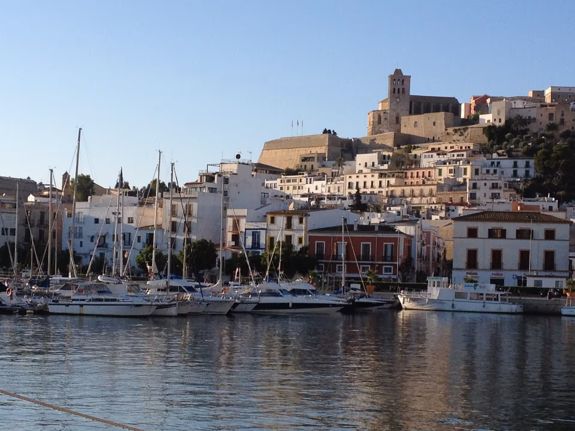 Ibiza Town marina view with boats and UNESCO Dalt Vila hilltop at dusk, perfect for a guided night tour