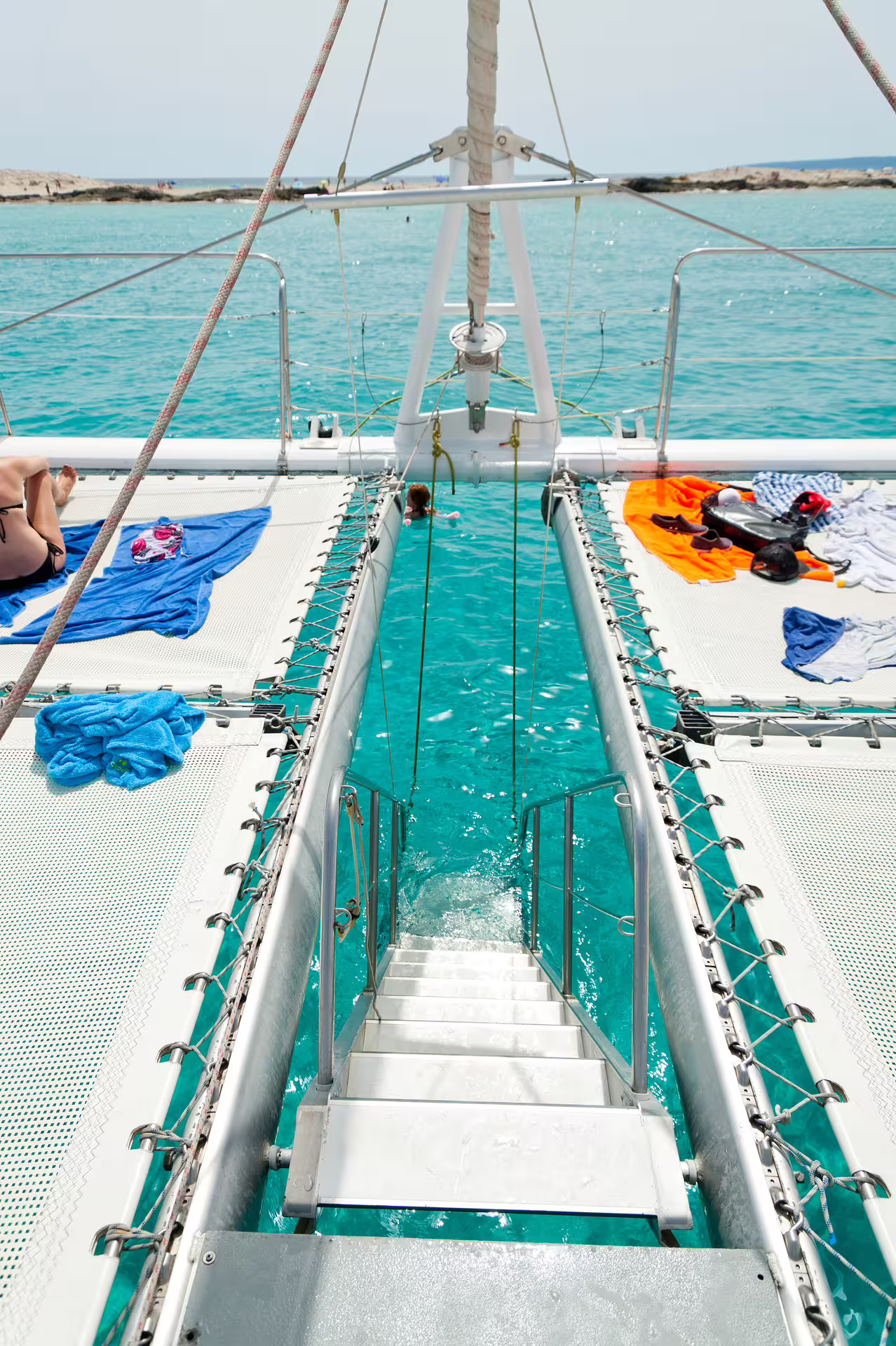 Catamaran swim ladder over turquoise Illetas waters, Ibiza to Formentera sailing tour with food included