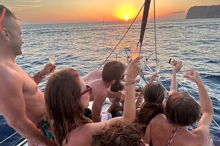 Group enjoying sunset sailing on Ibiza & Formentera trip, toasting with champagne on a yacht, capturing vibrant sea views.
