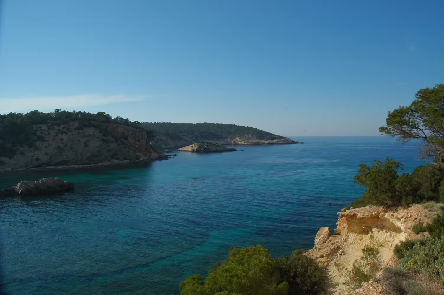 Scenic Ibiza island tour by bus view of turquoise bay and rugged cliffs, guided coastal lookout in Es Vedrà area