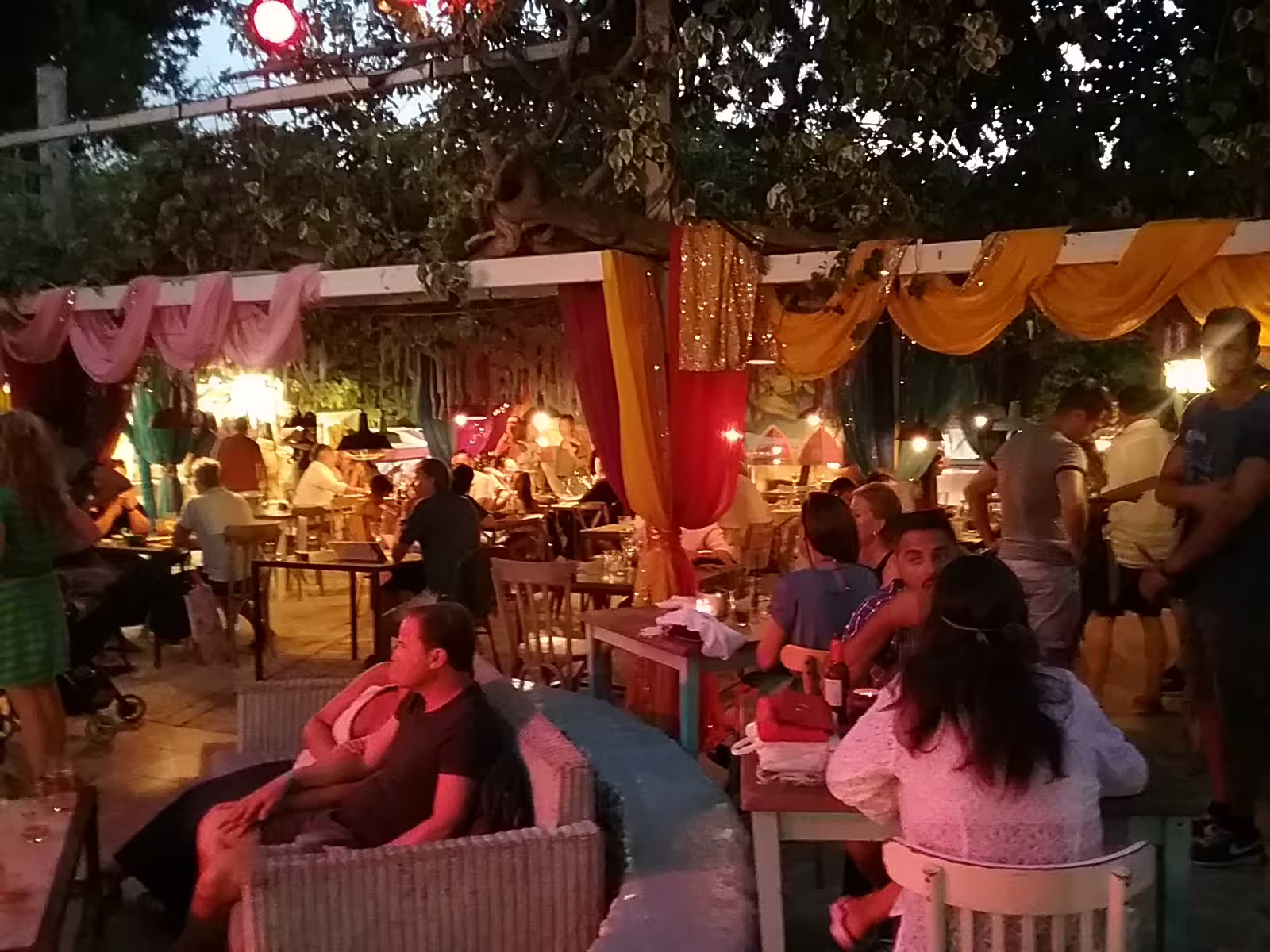 Evening dining area at Las Dalias hippie market, Ibiza sunset tour by bus, with colorful drapes and warm lights