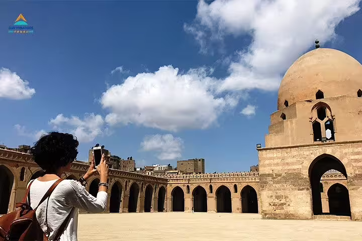 Traveler photographing Ibn Tulun Mosque courtyard in Islamic Cairo, Egypt, on guided historical mosques tour