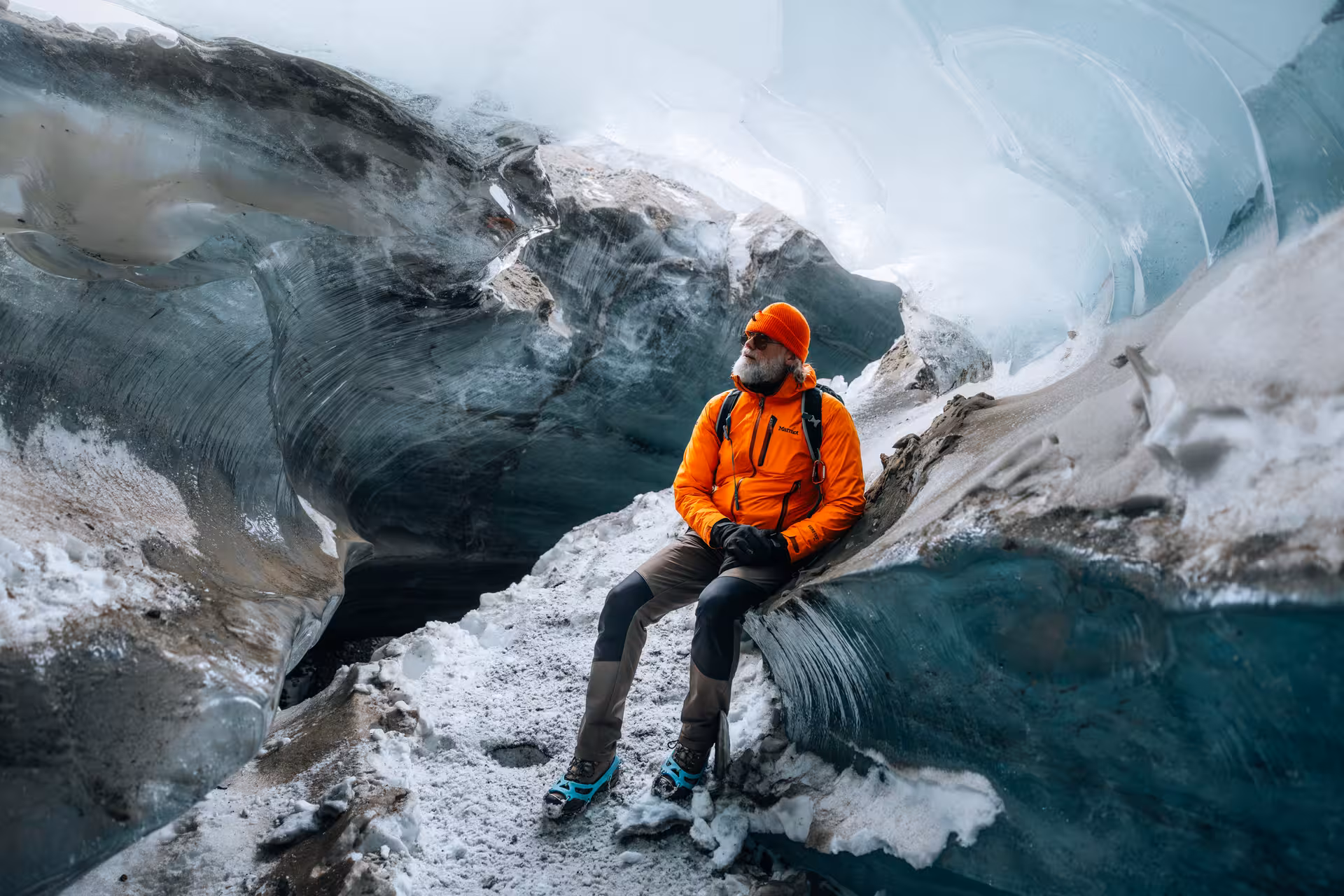 Traveler in orange gear inside a blue ice cave on a Gullfoss glacier tour with Glacier Monster Truck ride