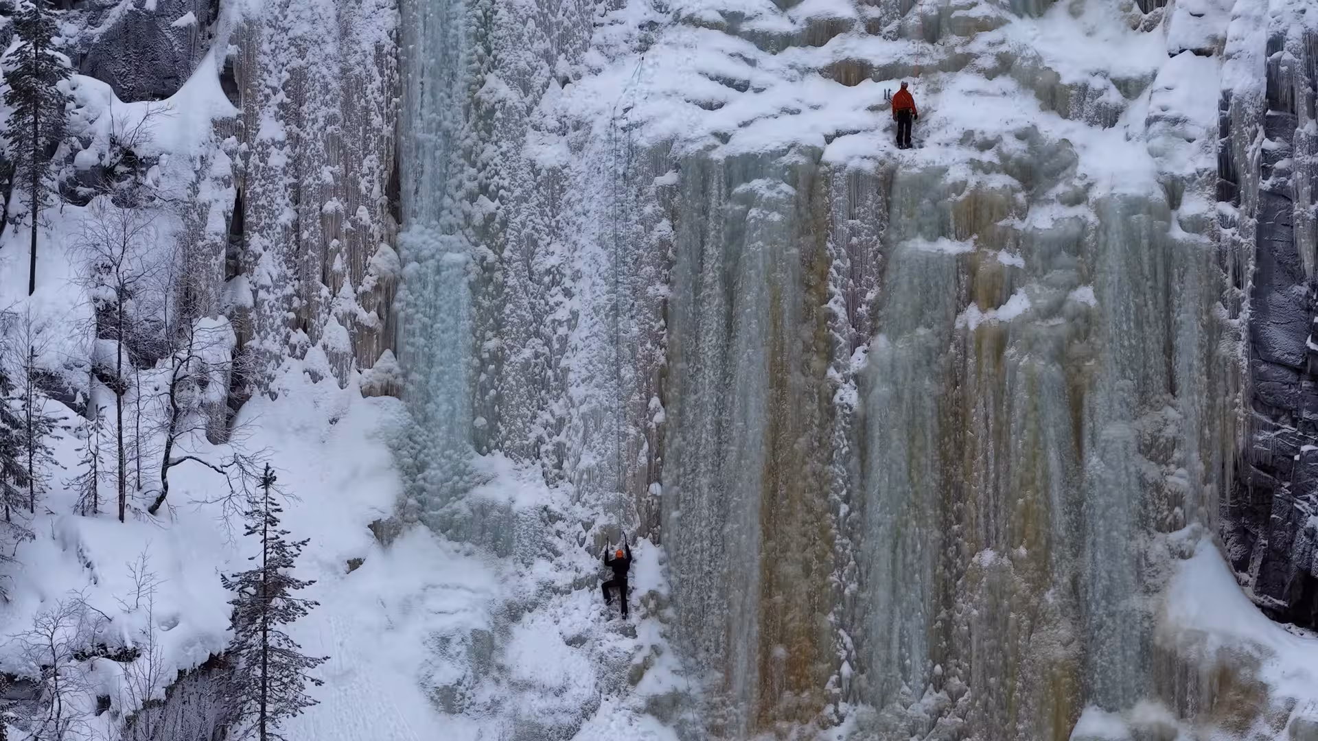Close-up of ice climbers scaling a frozen waterfall in Rovaniemi, showcasing the rugged icy terrain.
