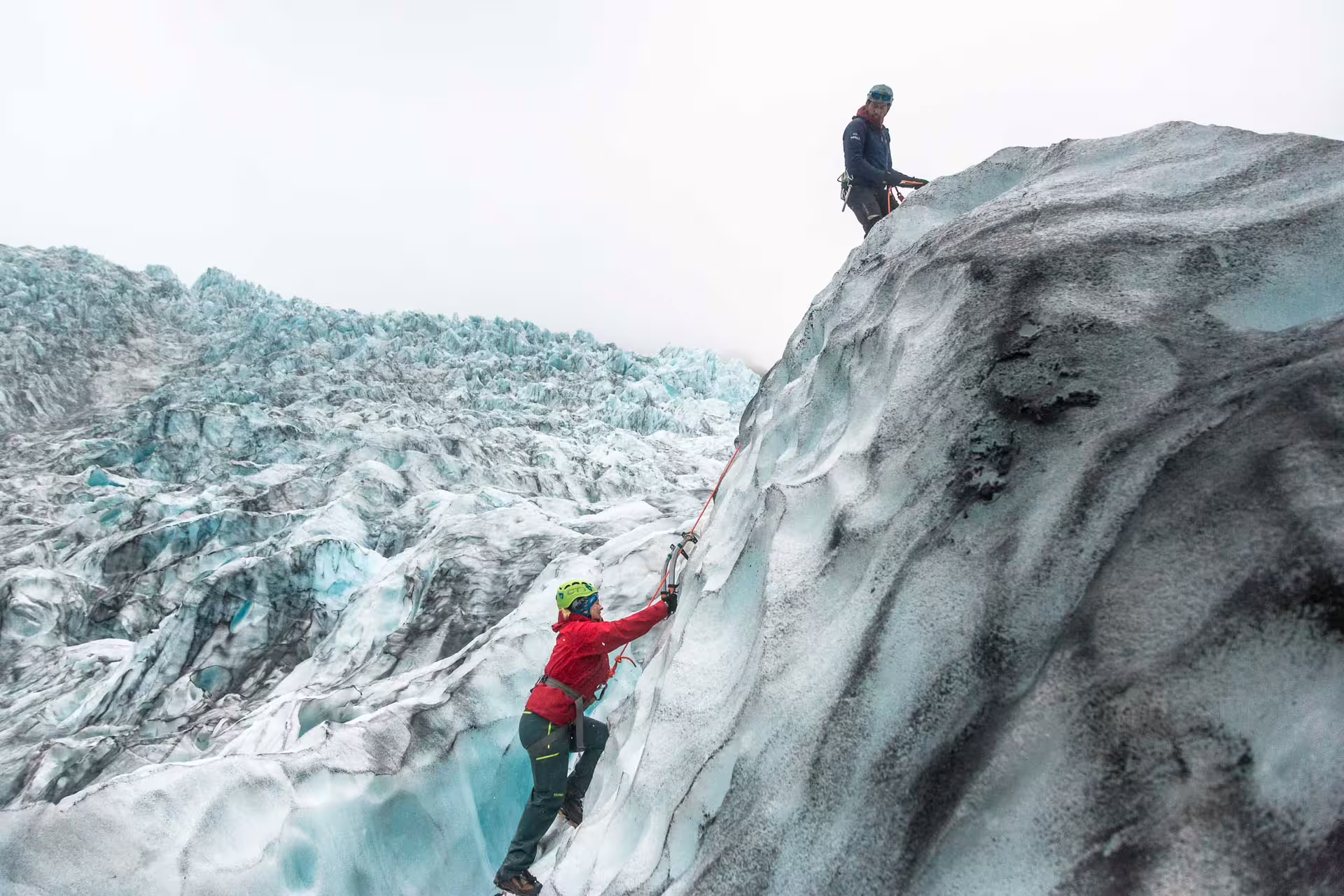 Two climbers ascending a glacial ice wall with ropes and helmets at Skaftafell glacier, Iceland
