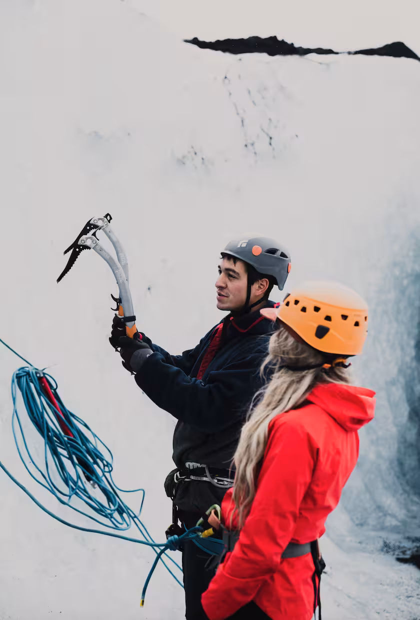 Ice climbing guide demonstrating ice axe technique to student on Solheimajokull glacier