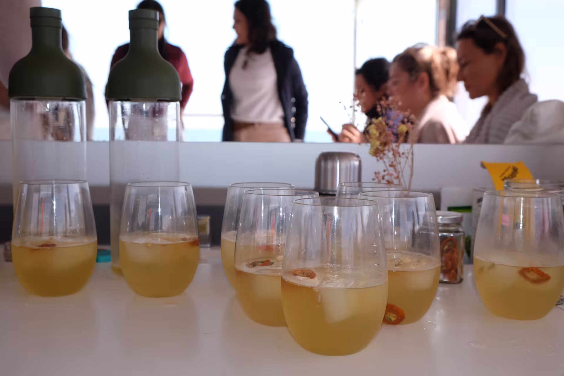 Iced tea served in stemless glasses during a tea ceremony tasting, with guests chatting in the background