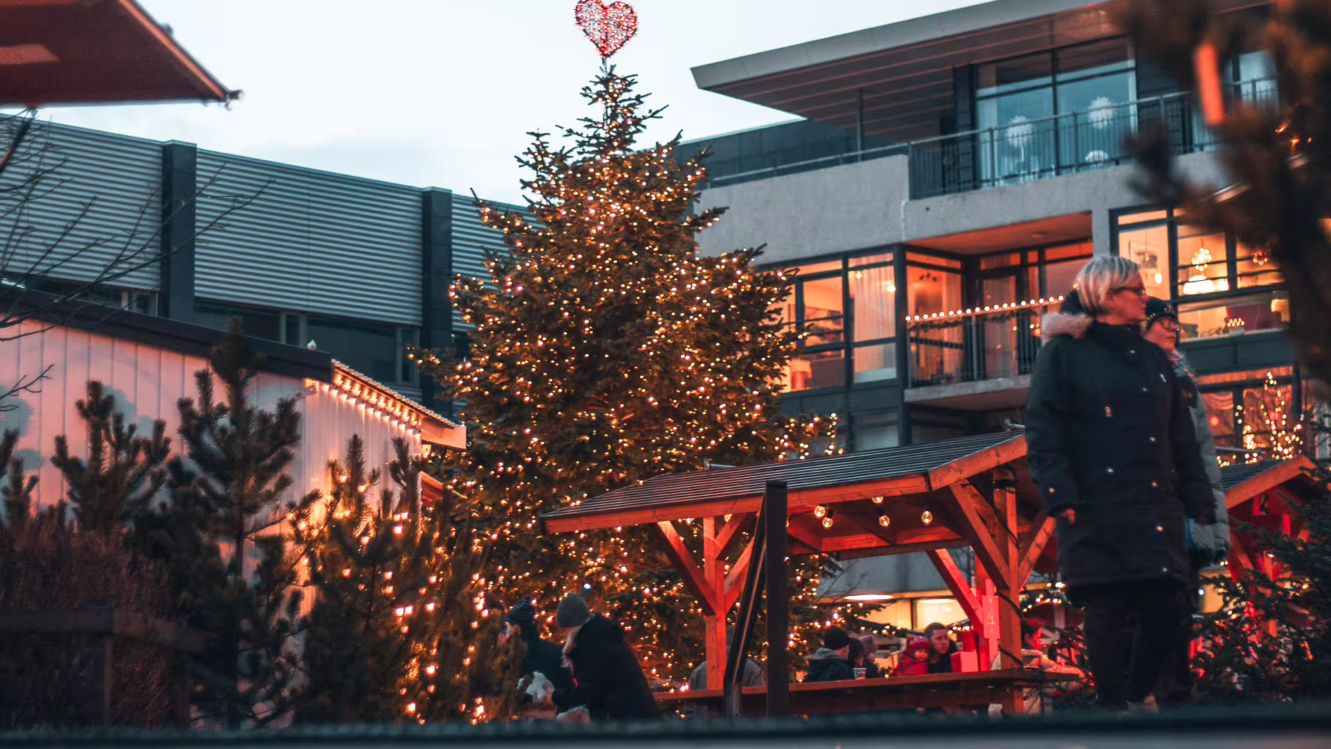 Illuminated Christmas tree with heart topper at outdoor Icelandic advent market with festive lights